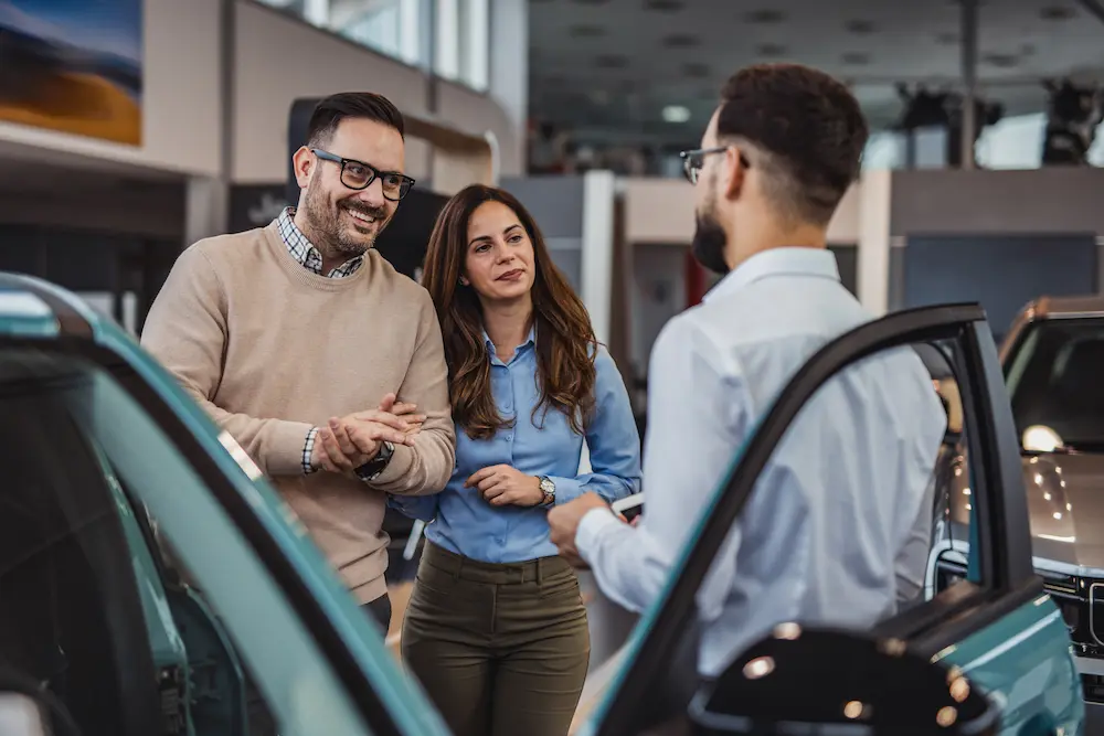 Man looks at vehicle options with friendly salesperson